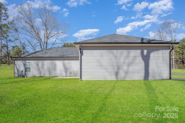 view of side of home with a lawn and roof with shingles