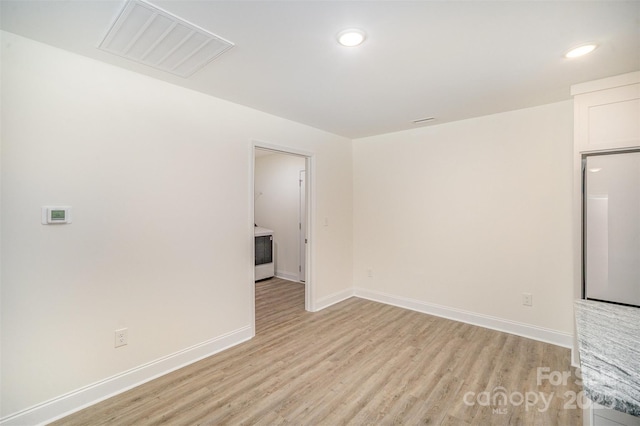 empty room with light wood-style floors, recessed lighting, visible vents, and baseboards