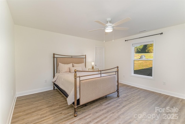 bedroom featuring a ceiling fan, visible vents, baseboards, and wood finished floors