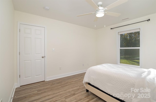 bedroom featuring visible vents, baseboards, ceiling fan, and wood finished floors