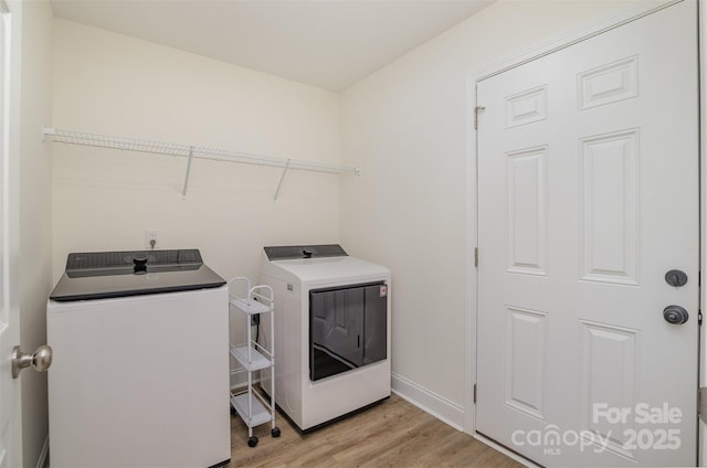 laundry area with laundry area, light wood-style flooring, baseboards, and washer and dryer