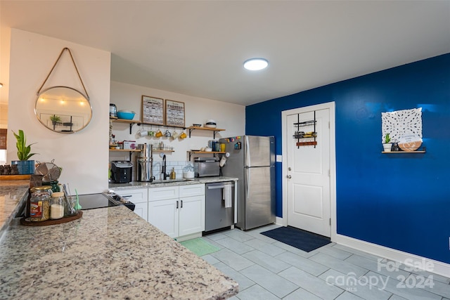 kitchen with white cabinets, sink, light stone countertops, and stainless steel appliances