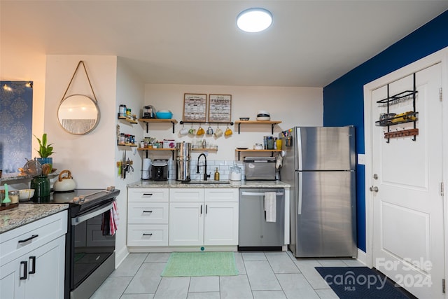 kitchen with white cabinets, stainless steel appliances, light stone counters, and sink