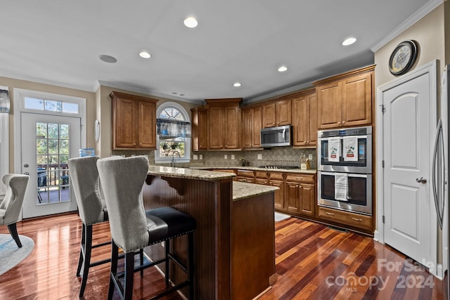 kitchen with appliances with stainless steel finishes, a wealth of natural light, and dark wood-type flooring