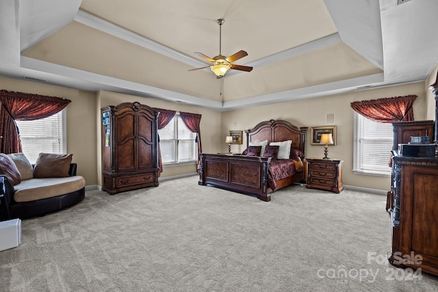 carpeted bedroom featuring a raised ceiling, multiple windows, and ceiling fan