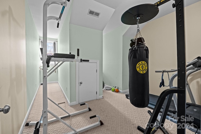 workout room with light colored carpet and vaulted ceiling