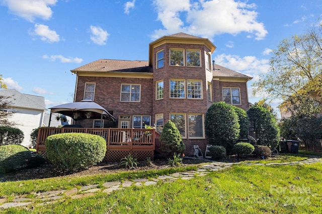 back of property featuring a gazebo, a wooden deck, and a lawn