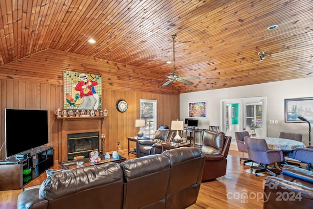 living room with wood walls, vaulted ceiling, wood ceiling, light wood-type flooring, and french doors