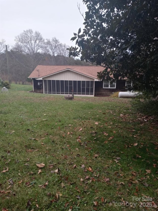 rear view of house featuring a lawn and a sunroom