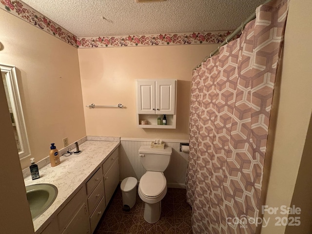 bathroom featuring a textured ceiling, toilet, vanity, and tile patterned flooring