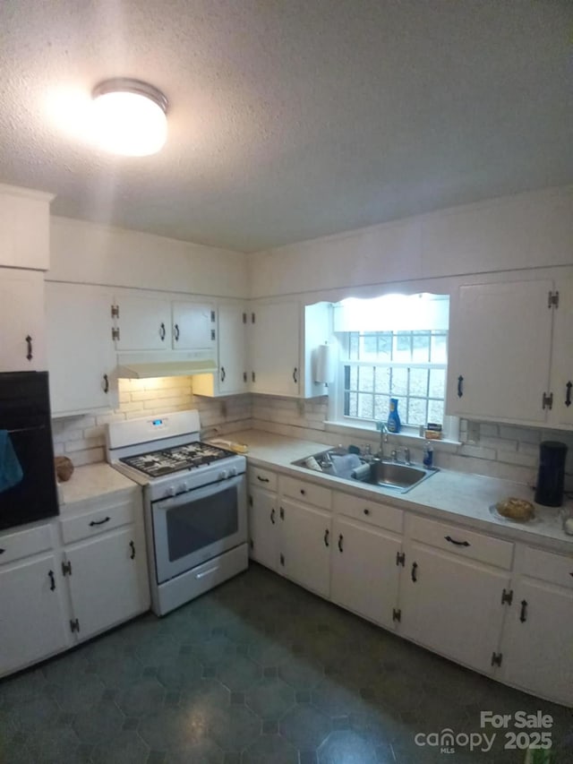 kitchen with white cabinetry, decorative backsplash, white range with gas cooktop, oven, and sink