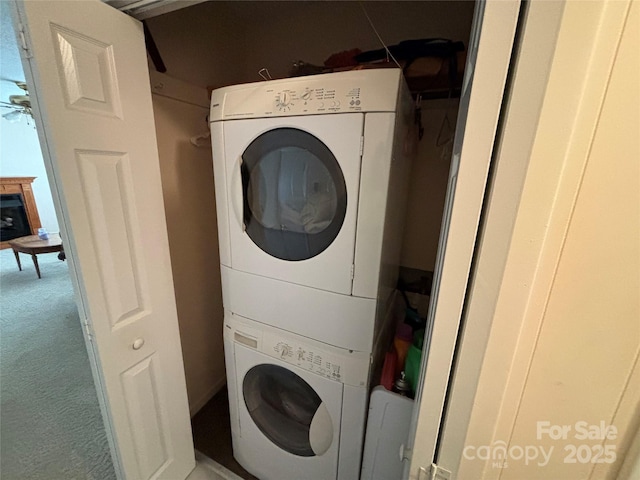 laundry room featuring stacked washer and dryer, ceiling fan, and carpet