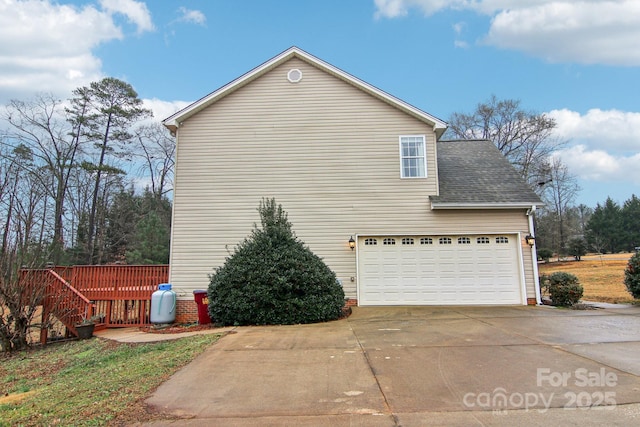 view of side of property featuring a garage, driveway, and roof with shingles