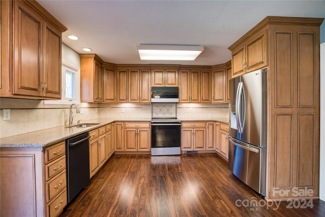 kitchen with dark hardwood / wood-style flooring, decorative backsplash, sink, light stone countertops, and appliances with stainless steel finishes