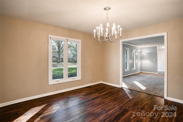 unfurnished dining area featuring hardwood / wood-style floors, a notable chandelier, and a textured ceiling