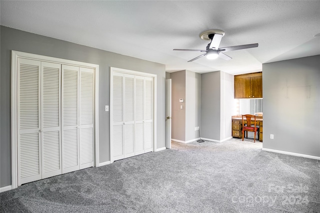 unfurnished bedroom with ceiling fan, multiple closets, and carpet