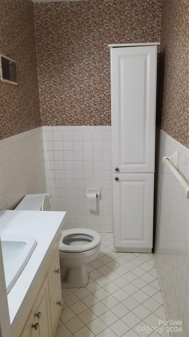 bathroom with tile patterned floors, vanity, tile walls, and toilet