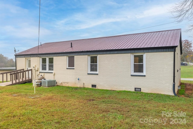 back of property with central AC and a lawn