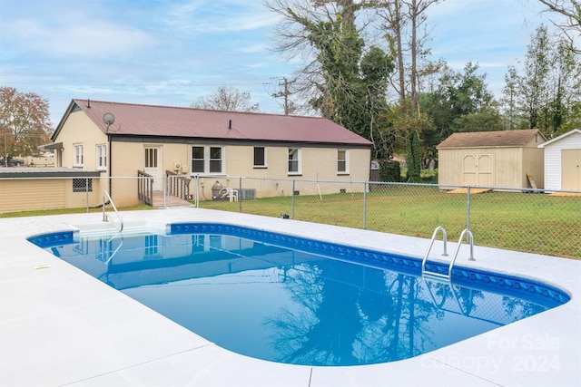 view of swimming pool featuring a lawn and a storage shed