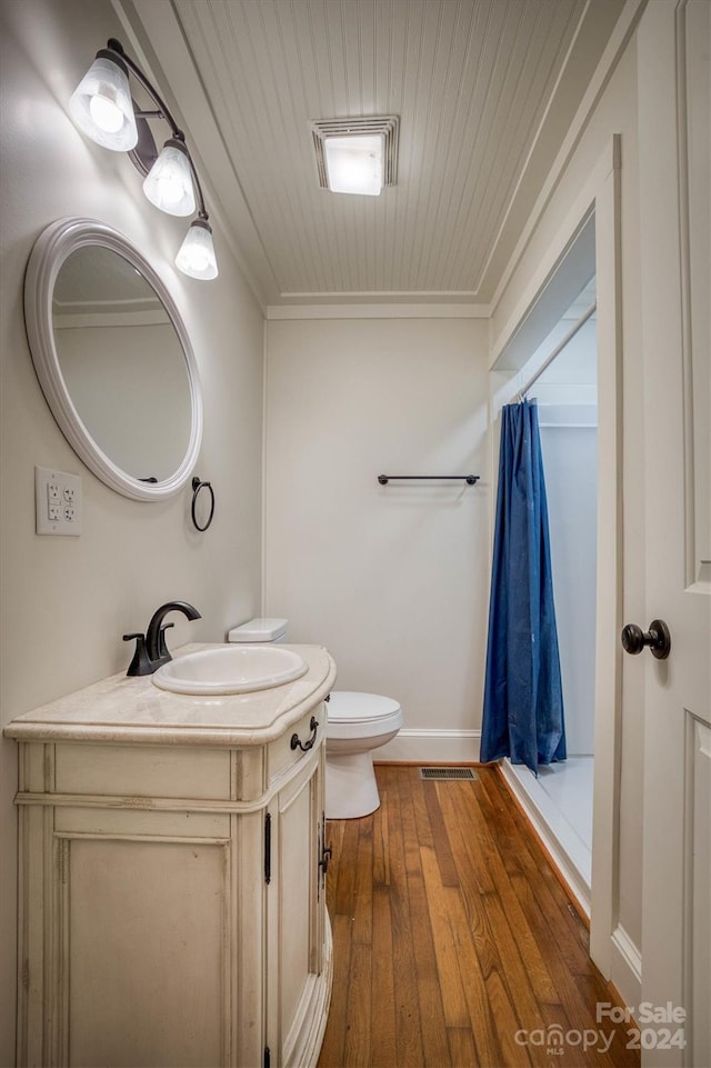 bathroom with toilet, curtained shower, hardwood / wood-style flooring, and ornamental molding