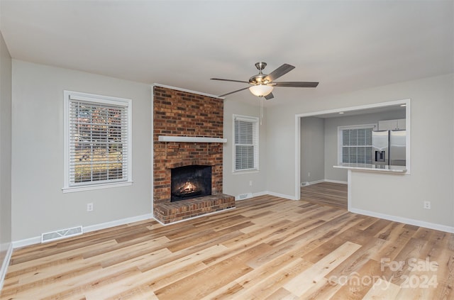 unfurnished living room with light wood-type flooring, ceiling fan, and a fireplace