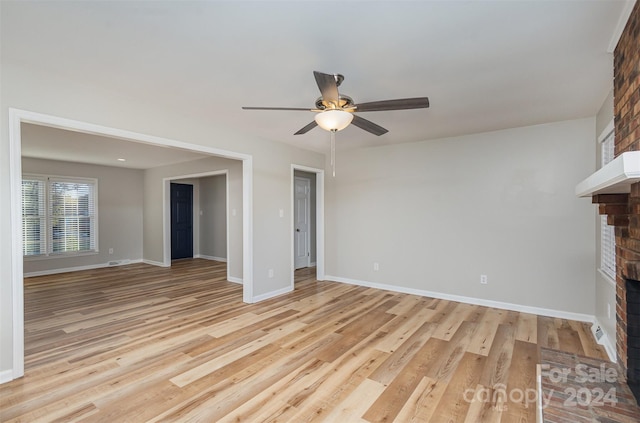 unfurnished living room featuring light wood-type flooring, ceiling fan, and a fireplace