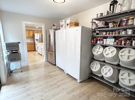 kitchen featuring stainless steel fridge, light hardwood / wood-style floors, white refrigerator, and stainless steel refrigerator with ice dispenser