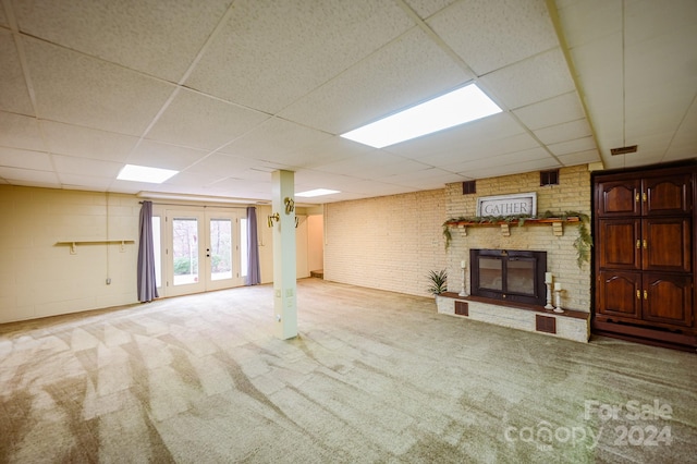 basement with a paneled ceiling, carpet floors, a fireplace, and french doors