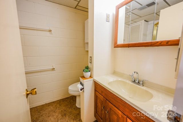 bathroom featuring a drop ceiling, toilet, and vanity