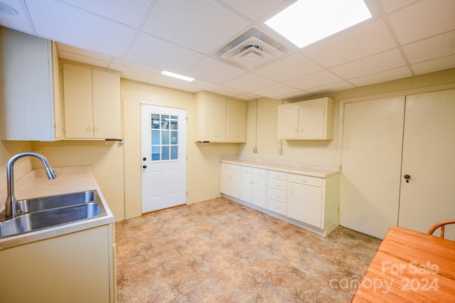 kitchen with cream cabinetry, a drop ceiling, and sink