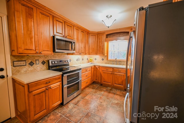 kitchen featuring appliances with stainless steel finishes, tasteful backsplash, tile patterned floors, and sink