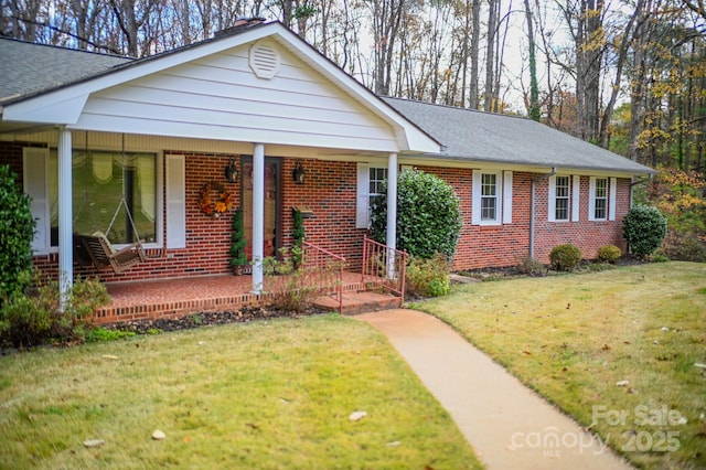 183 Creekside Dr, Forest City, NC 28043 - ranch-style house featuring brick siding, a porch, a front yard, and a shingled roof