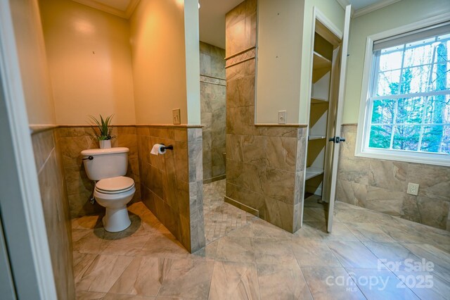 183 Creekside Dr, Forest City, NC 28043 - full bath with tile walls, walk in shower, ornamental molding, toilet, and wainscoting
