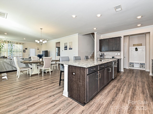 kitchen with dark brown cabinetry, sink, pendant lighting, a breakfast bar area, and a center island with sink