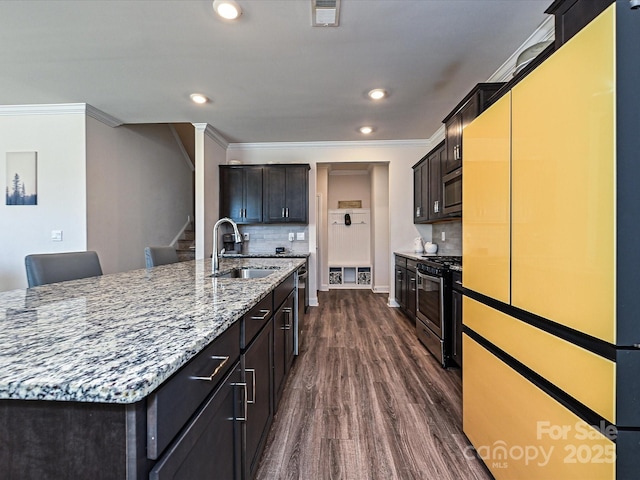 kitchen with appliances with stainless steel finishes, dark hardwood / wood-style flooring, tasteful backsplash, sink, and a center island with sink