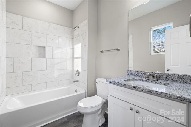 full bathroom featuring vanity, wood-type flooring, tiled shower / bath combo, and toilet