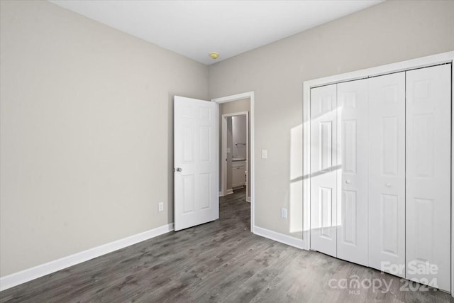 unfurnished bedroom with dark hardwood / wood-style floors and a closet