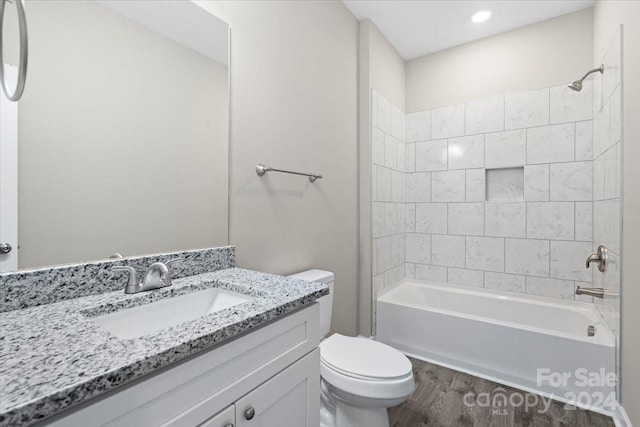 full bathroom featuring vanity, wood-type flooring, tiled shower / bath combo, and toilet