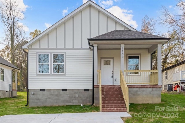 view of front facade with a porch, central AC, and a front lawn