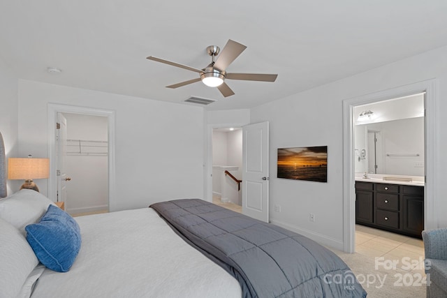 bedroom featuring ensuite bathroom, a walk in closet, ceiling fan, light tile patterned floors, and a closet