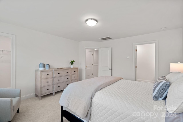 bedroom with a walk in closet, light carpet, and a closet