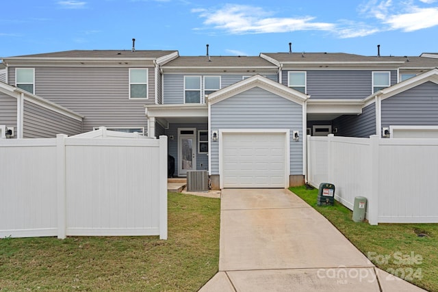 view of front of house featuring a garage, a front lawn, and central air condition unit