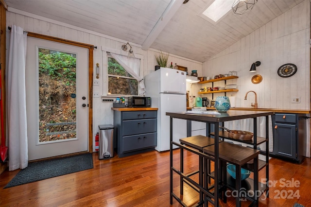 kitchen with lofted ceiling with skylight, white fridge, wooden ceiling, and hardwood / wood-style flooring