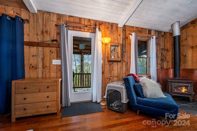 sitting room with plenty of natural light, wood walls, dark hardwood / wood-style flooring, and a wood stove