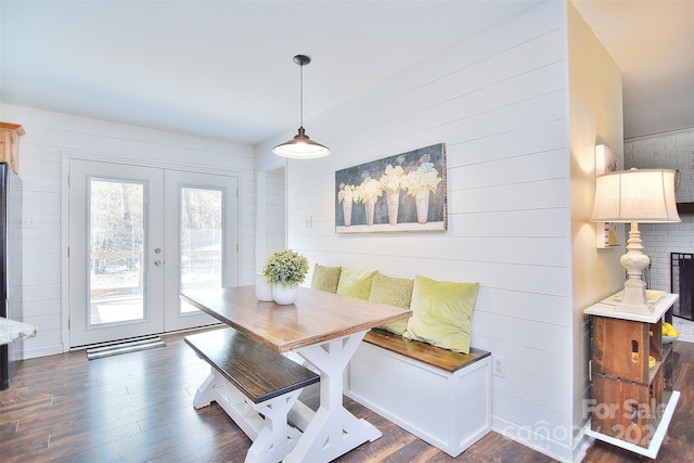 dining space with french doors, breakfast area, dark hardwood / wood-style floors, and wood walls