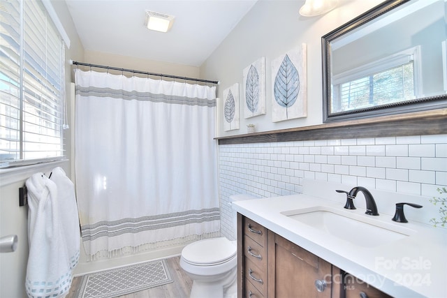 full bathroom featuring toilet, a healthy amount of sunlight, tile walls, and wood-type flooring