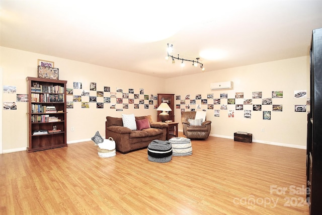 living room with a wall mounted air conditioner, rail lighting, and light hardwood / wood-style flooring