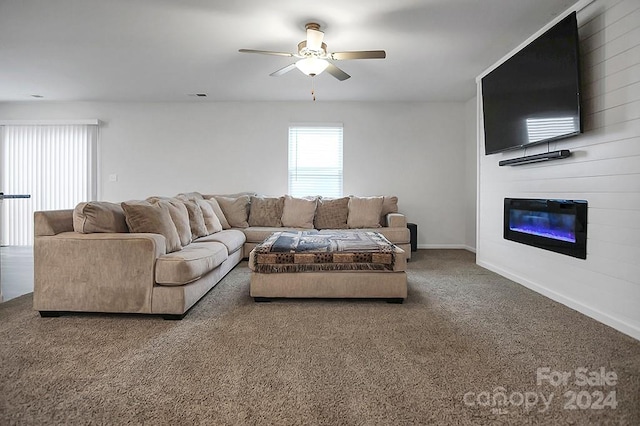 living room featuring carpet, a large fireplace, and ceiling fan