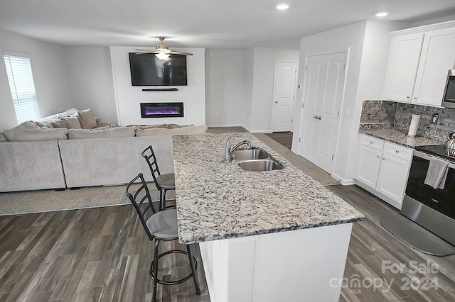 kitchen featuring a center island with sink, white cabinetry, appliances with stainless steel finishes, sink, and a breakfast bar area