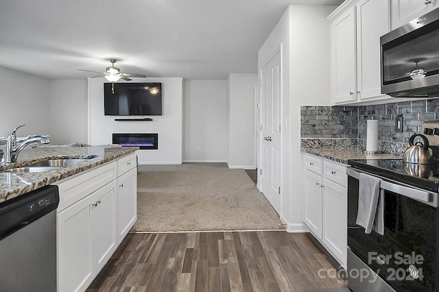 kitchen featuring stainless steel appliances, sink, dark stone countertops, white cabinets, and dark hardwood / wood-style flooring